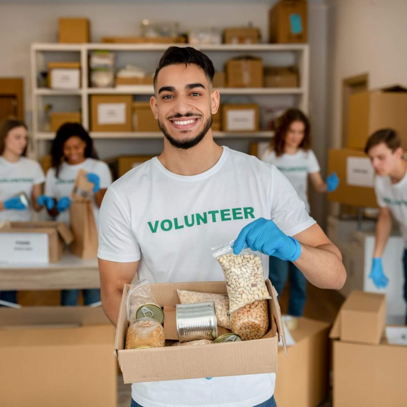 young-arab-volunteer-working-at-charity-center-holding-food-donation-box-and-smiling-to-camera.jpg